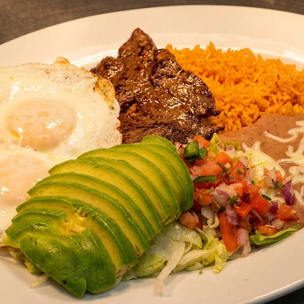 A white plate with steak, two fried eggs, rice, refried beans, sliced avocado, and pico de gallo.